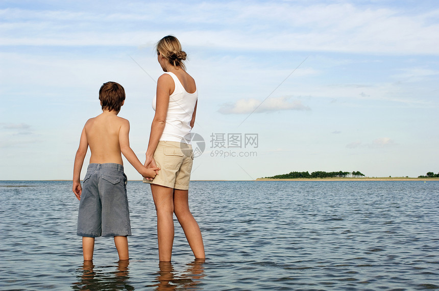母亲和儿子在享受海景时手牵手的近视图片