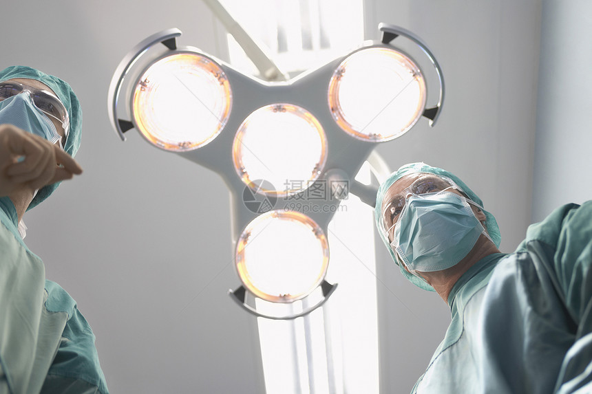 手术区两名外科医生在手术室手电灯下低角度观察操作天花板从业者剧院房间情况程序医师医院视图图片