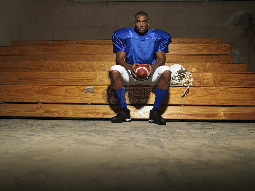 一个美国足球运动员的肖像 坐在板凳上 带着球图片