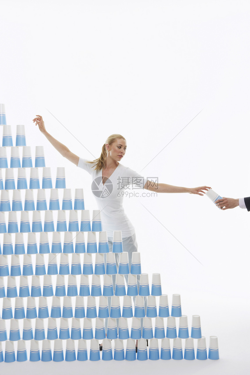 白色背景的堆叠金字塔式金字塔塑料杯手传递妇女图片
