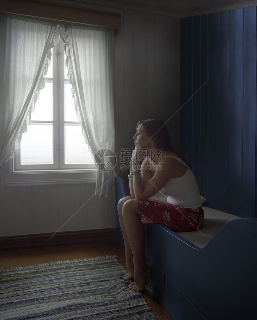 一位年轻 体贴深思熟虑和悲伤的女士单独坐在房间里的侧面风景图片