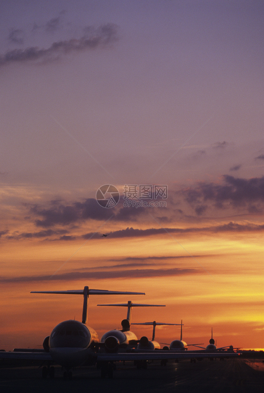 日落时坐落在Tarmac旅行排列航空客运飞机喷射喷射机空格飞机机场背光图片