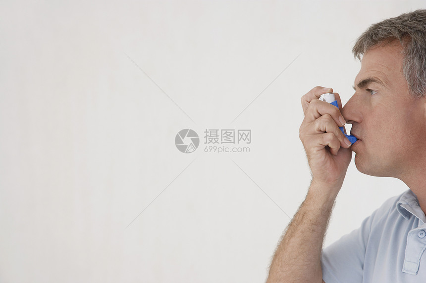 使用白色背景隔离吸入器的中年男子侧边视图Name图片