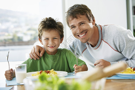快乐的父亲和儿子在餐桌上共进早餐的肖像家庭高清图片素材