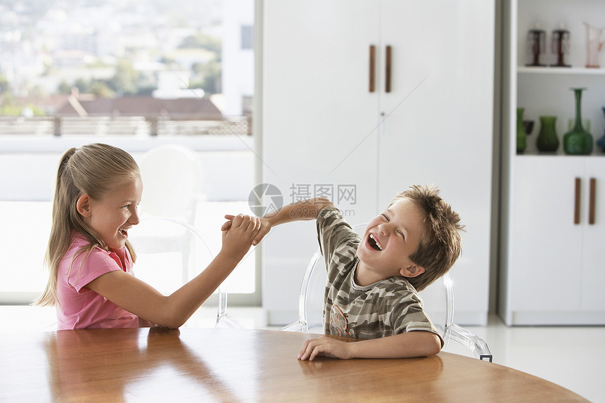 玩乐的年轻女孩和男孩在餐桌上打架图片