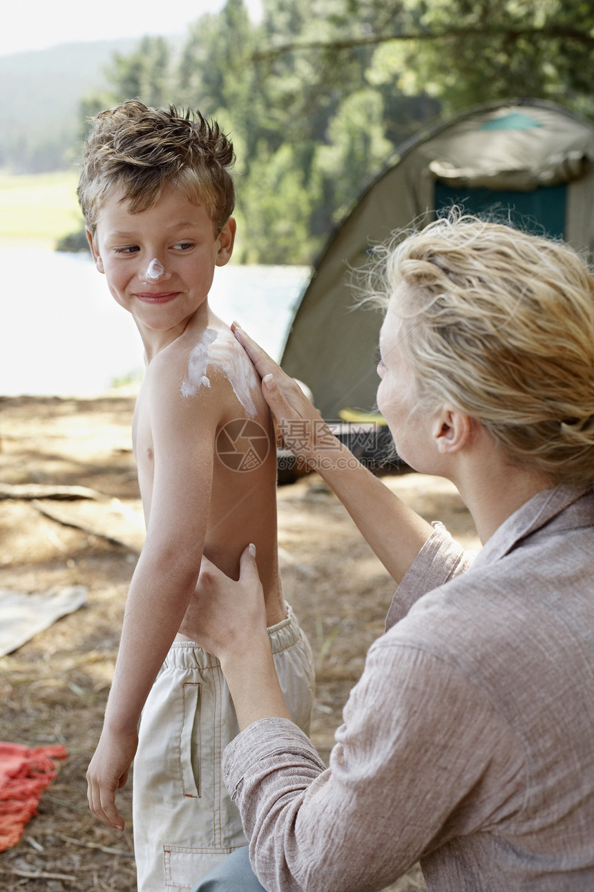 母亲在露营区儿子背上涂防晒霜图片