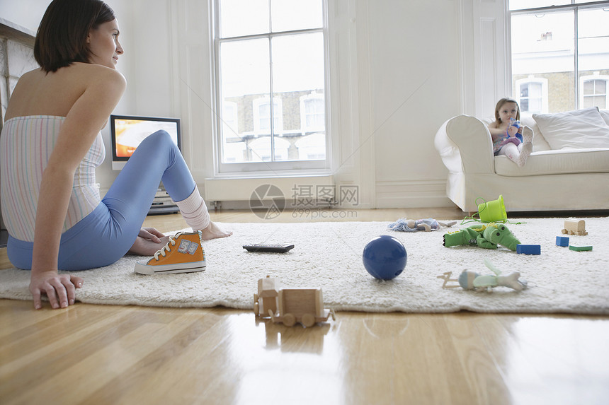 坐在地板上的女人 周围是玩具和沙发上的女儿图片