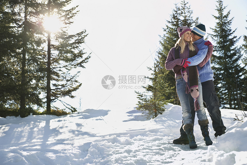 满身浪漫情侣站在雪覆盖的山丘上图片