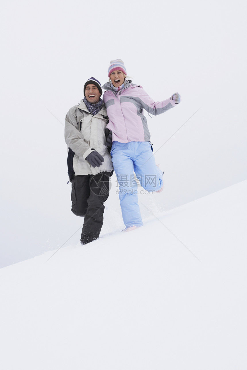 几人从雪覆盖的山丘低角视图下跑下来乐趣夫妻男子眼神男人拥抱女性休闲喜悦中年图片