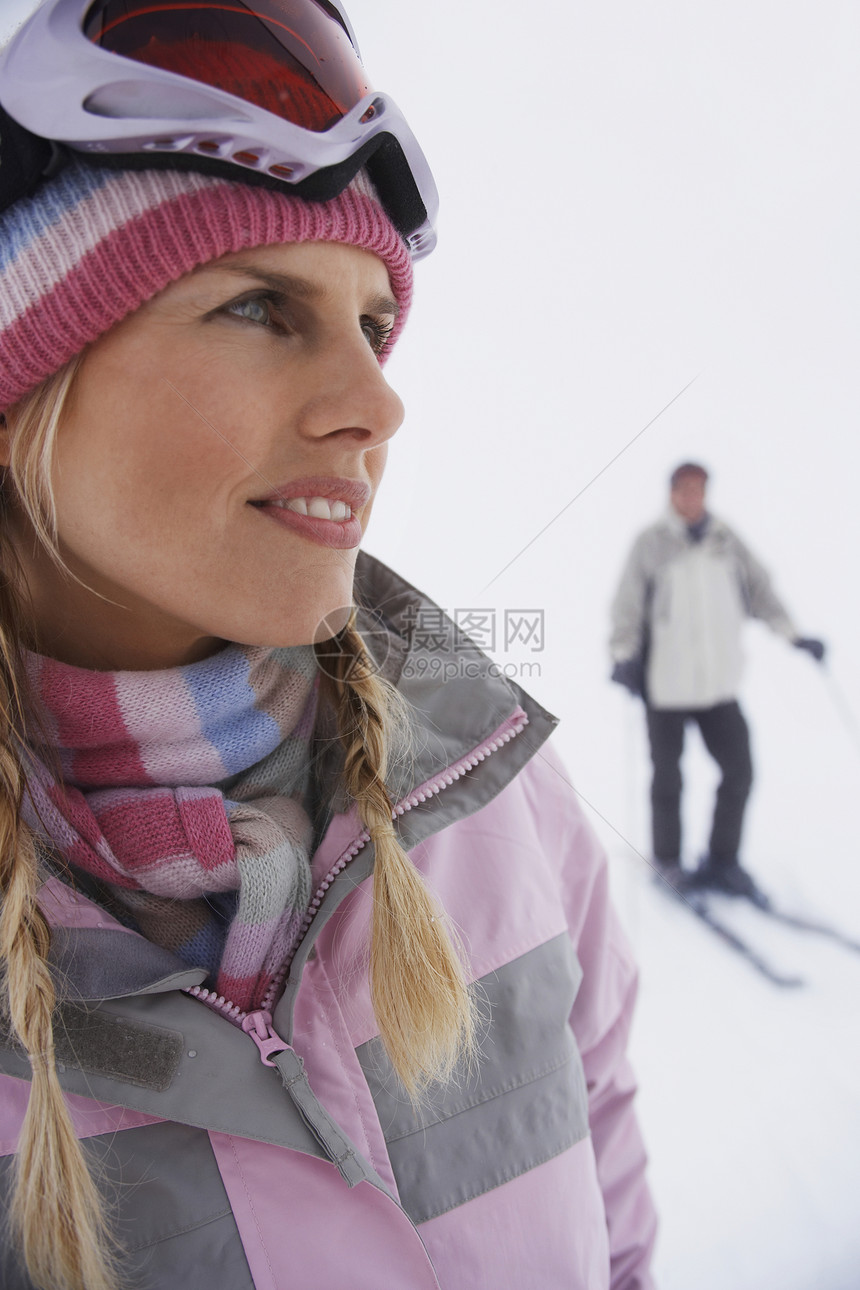 妇女站在滑雪斜坡上 男子站在背景滑雪上休闲滑雪镜针织帽成人服装活动沉思女性一个人中年人图片