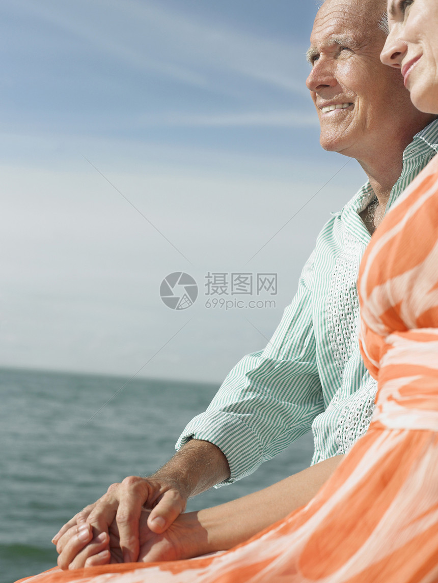 一对中年夫妇坐在水边的侧面视图图片