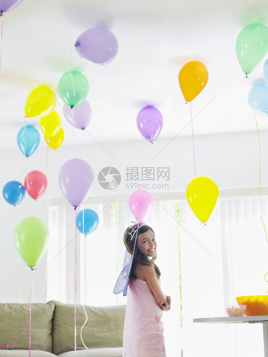 快乐的年轻女孩站在房间里 充满气球的房间图片