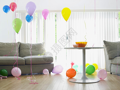 沙发旁的客厅里满是多彩气球庆典地板地面房间桌子水平房子阳光闲暇派对背景图片