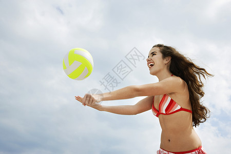 沙滩上排球少女1617岁在海滩排球低角度看幸福卷发手臂头发一人运动低角度沙滩热情棕色背景