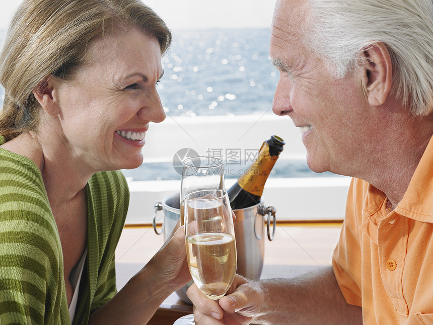 快乐的中年夫妇在游艇上喝香槟的侧景图片
