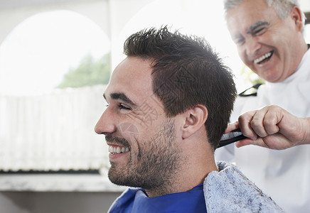 喜悦的男人在美发店理发时剪头发发型师顾客男性沙龙男士理发店梳子店铺工作发型头发护理高清图片素材