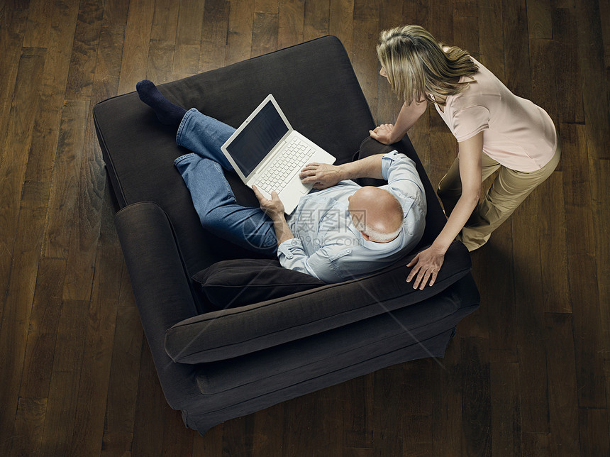 观看成年秃头男子的妇女的顶端视线是在家里沙发上使用笔记本电脑女士水平场景房子技术秃顶互联网房间家具空闲图片