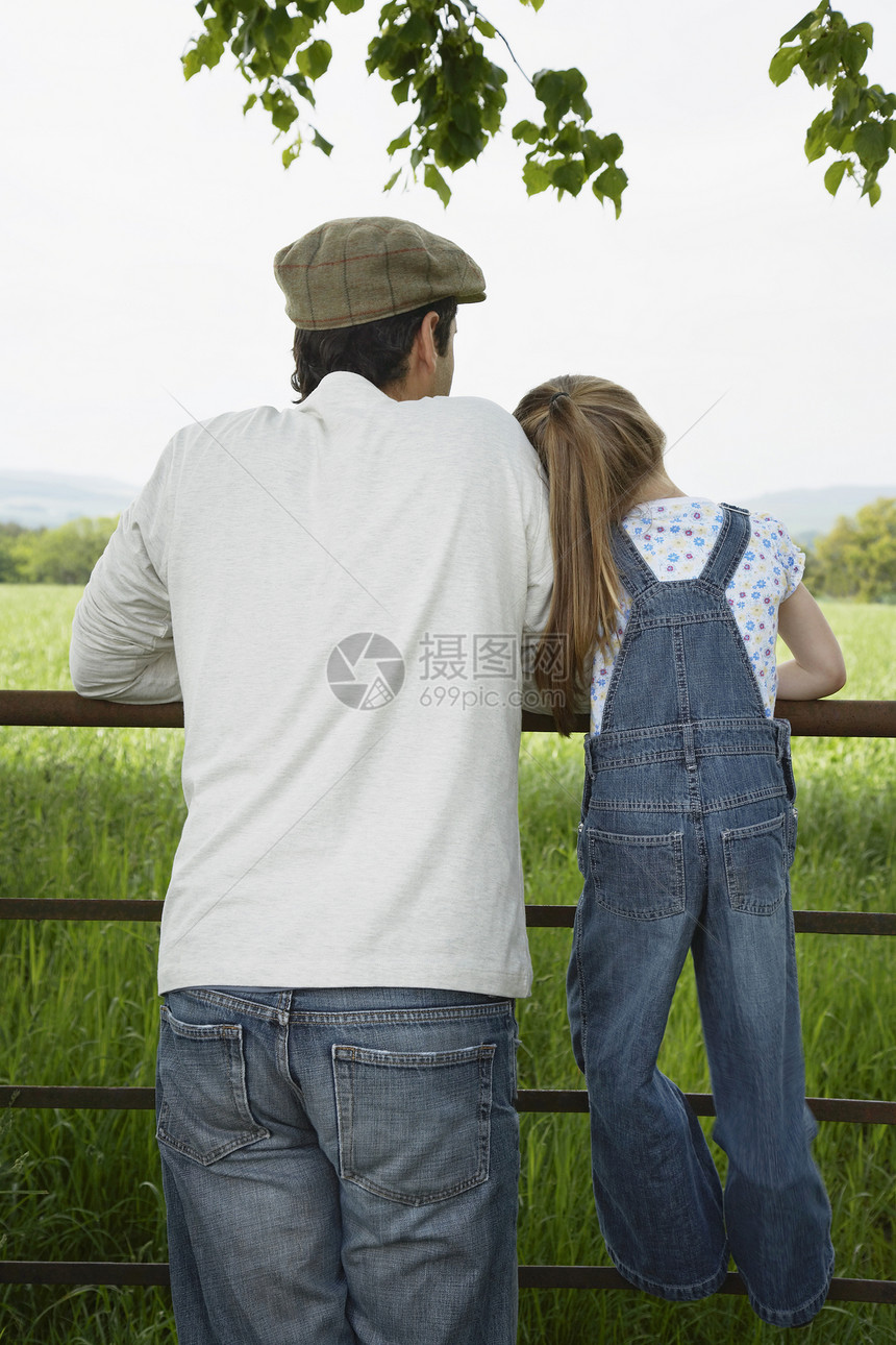 父亲和女儿的近视透过栅栏看风平浪静的地貌图片