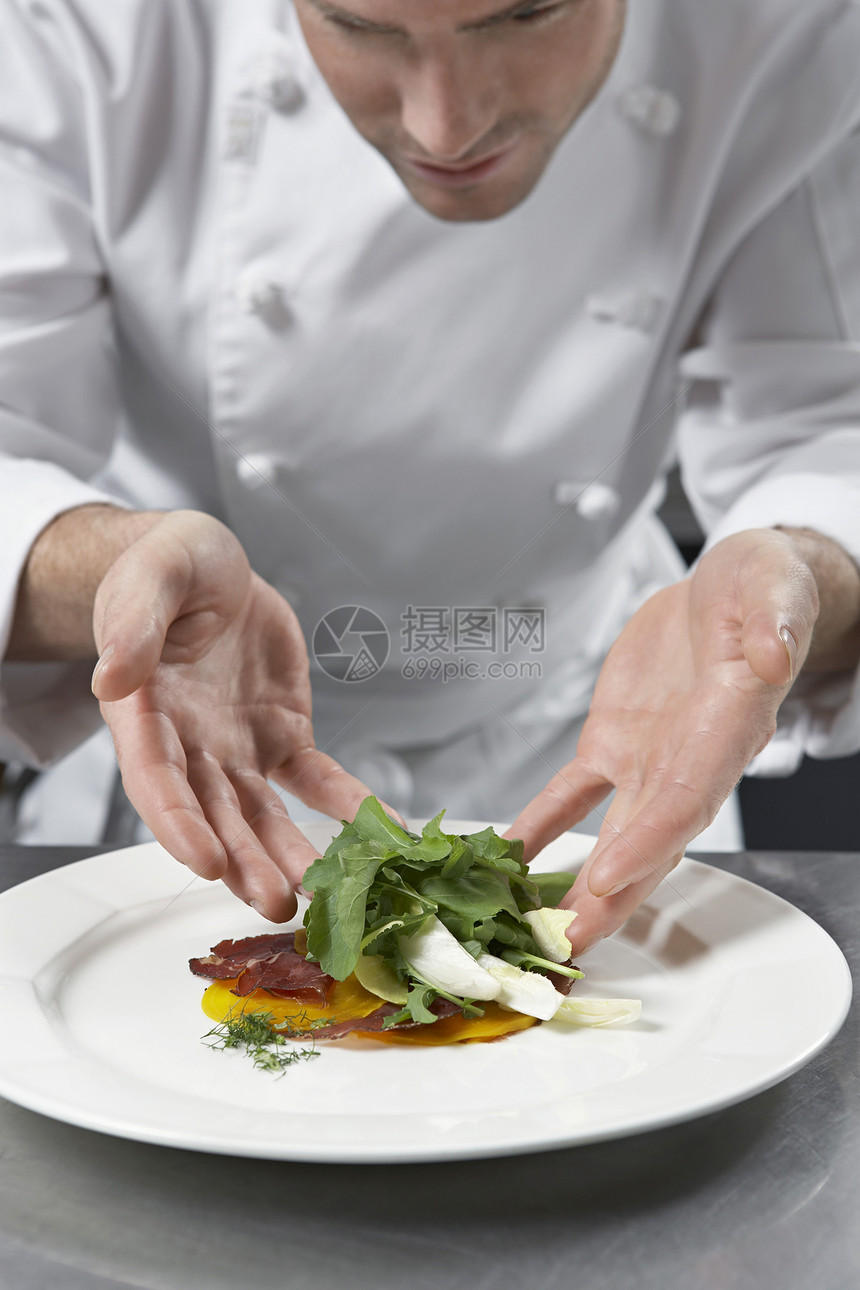 在厨房里做沙拉的男厨师商业晚餐专注男性食物准备裁剪绿色双手服务图片