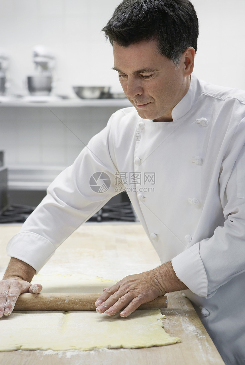 中年男性厨师在厨房里滚钱图片