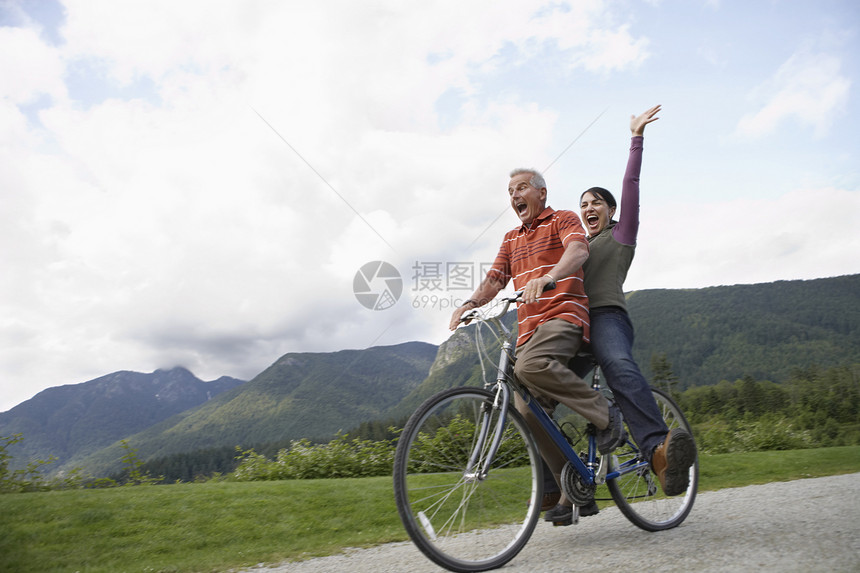 在乡村公路上骑自行车的中年夫妇喜悦的中年夫妇的低角度视角图片