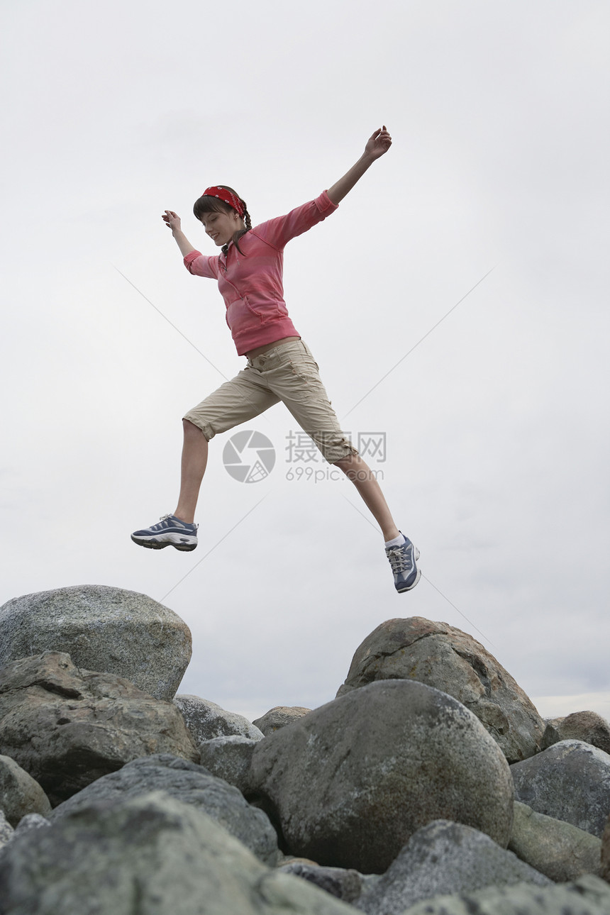 妇女用扶起的手在岩石上跳跃图片