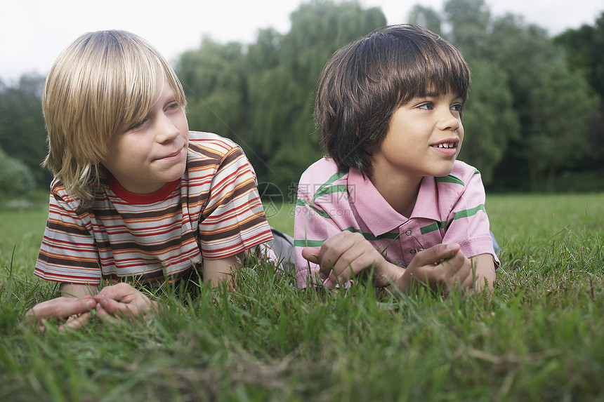 两个男孩 7-9 岁 躺在草地上看着别处的肖像图片