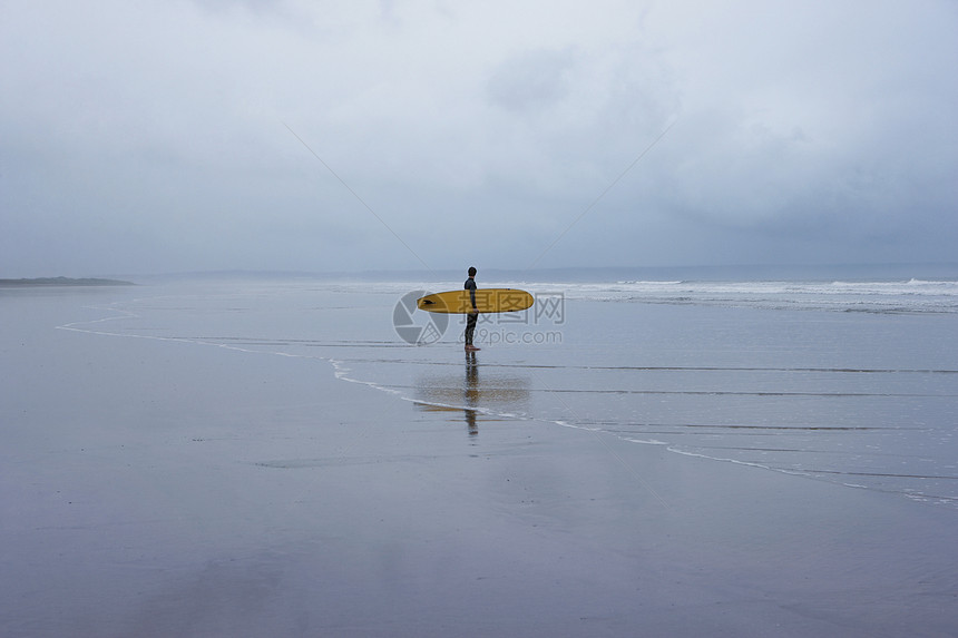 孤单冲浪者站在浅水边的浅水景图片