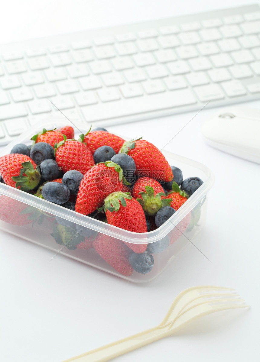 工作桌上的Berry混合午餐盒小吃笔记本电脑老鼠生活方式键盘水果白色浆果叶子图片