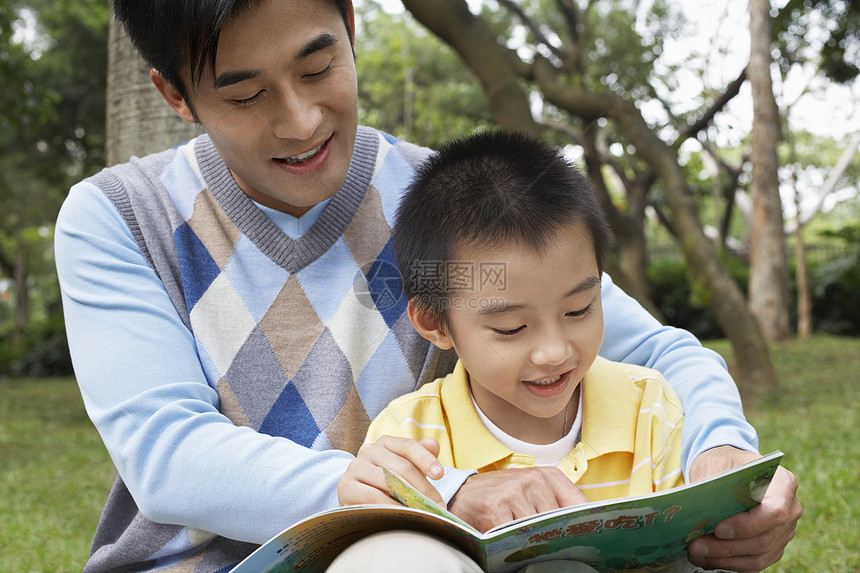 快乐的父亲和儿子在公园读书图片