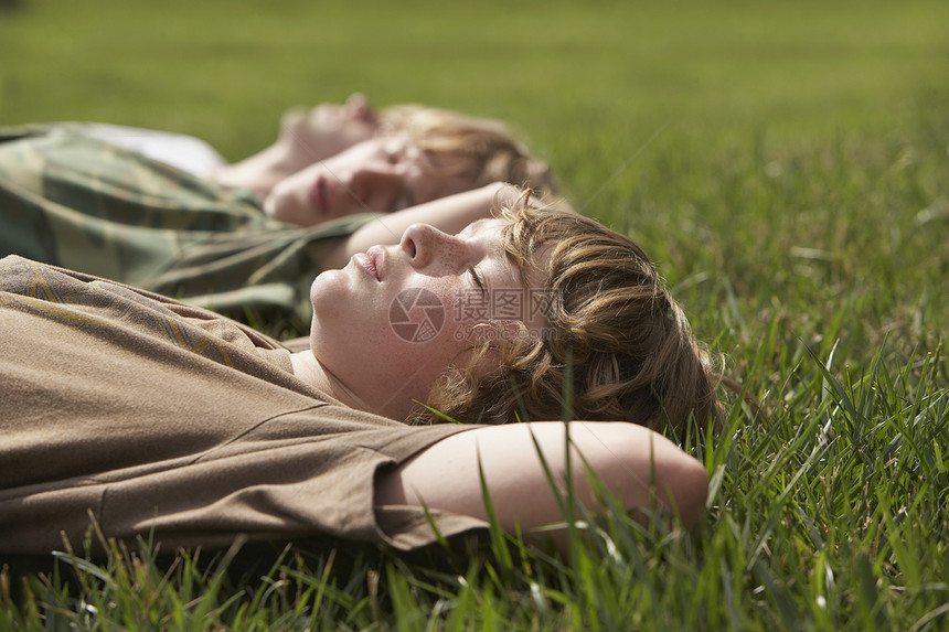 三个十几岁的兄弟(13至17岁)躺在草地上图片