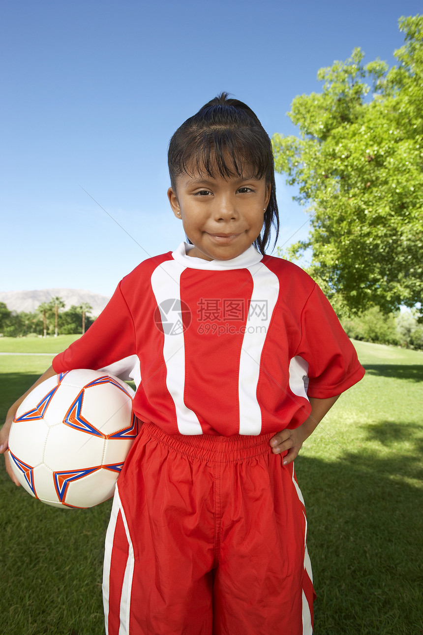 快乐年轻女孩的肖像 站在球场上踢足球图片