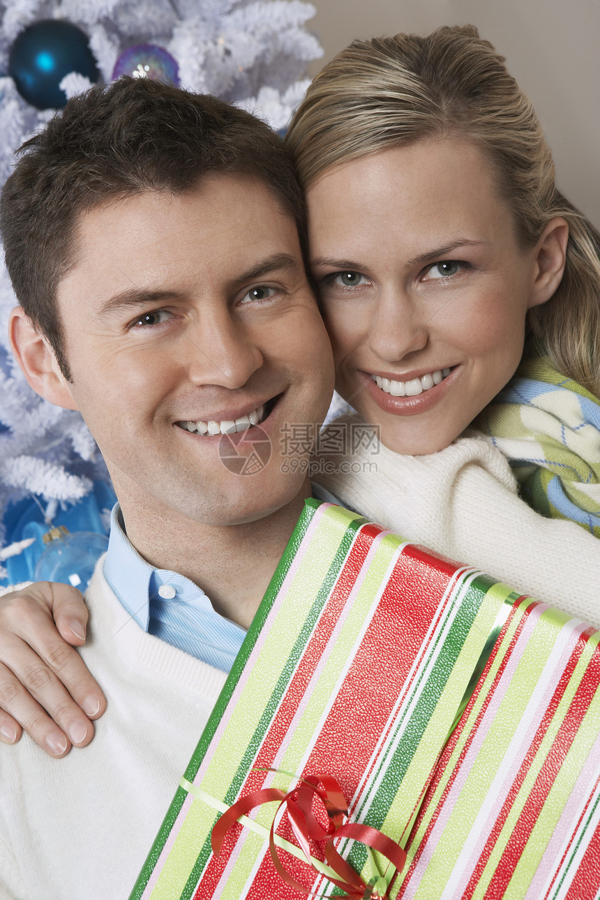 一对快乐的年轻白种夫妇 拿着圣诞树礼物的肖像图片