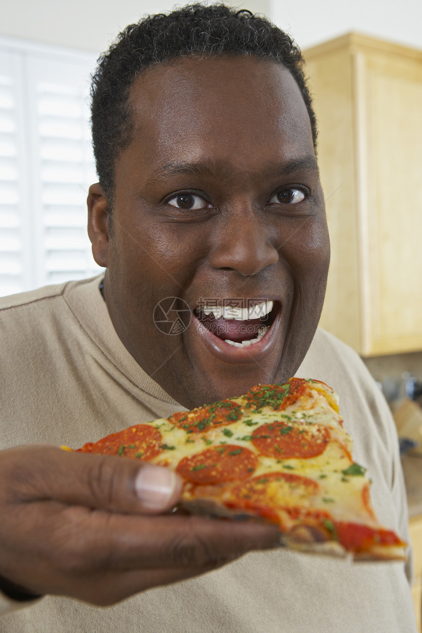 一位肥胖的非裔美国人在吃披萨的近距离肖像图片