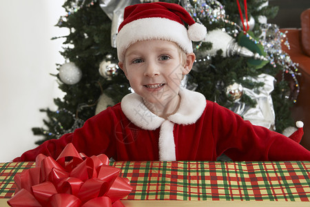 圣诞老人服装中可爱小男孩的肖像 穿着圣诞礼物 拿着圣诞礼物背景图片