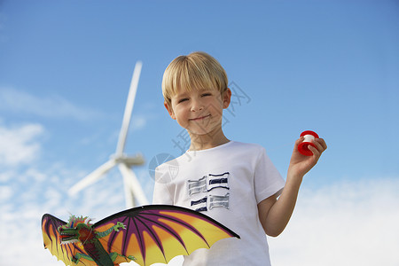 龙风筝一个可爱男孩的肖像 在风力农场拿着风筝背景