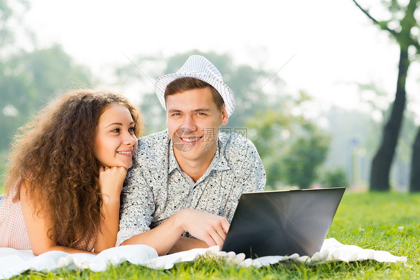 一对夫妇一起躺在公园里 带着笔记本电脑商业闲暇技术朋友们女性生活网络青年快乐幸福图片