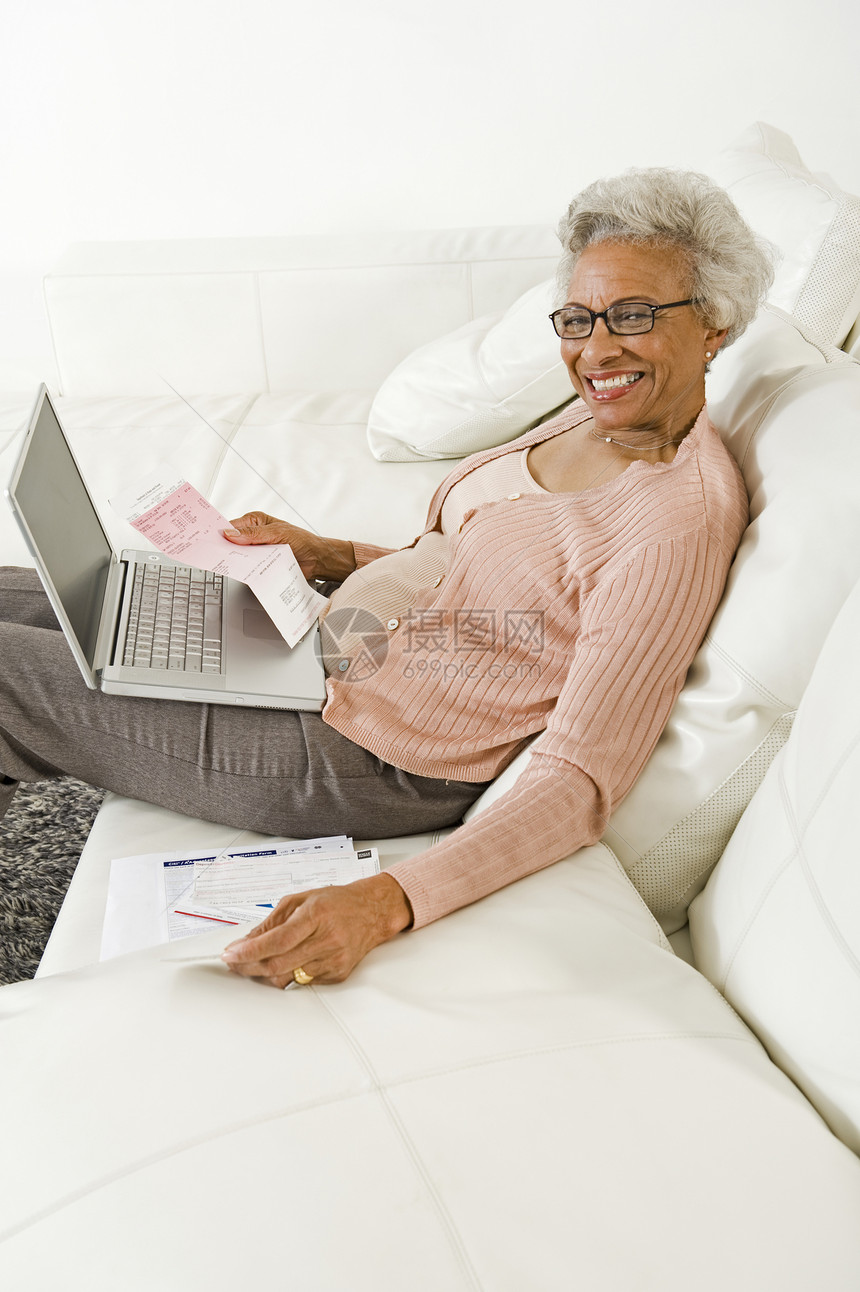 使用笔记本电脑的年长妇女财务眼镜开襟衫微笑混血女性快乐老年粉色家庭图片