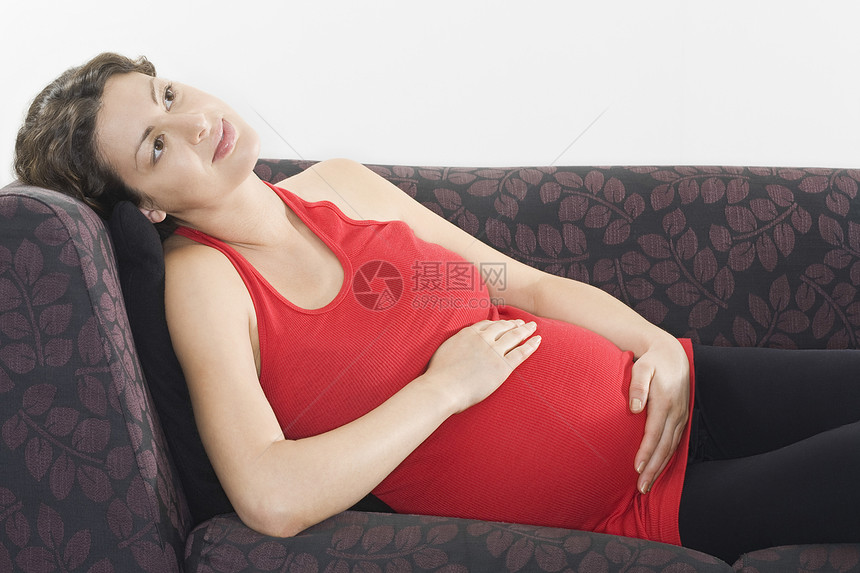 孕妇在沙发上放松微笑新生活母性腹部怀孕中年长椅大事头发沉思图片