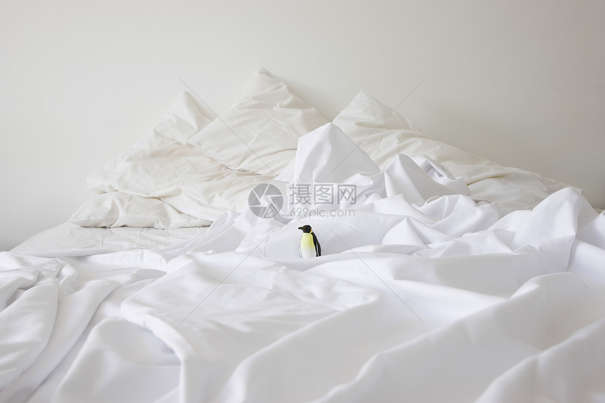 看见一只玩具企鹅在家里乱成一团的床上卧室模仿被单房间房子被子公寓塑像枕头白色图片