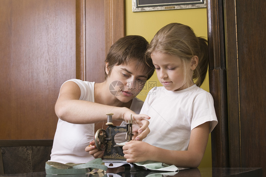 母亲和女儿在家里使用旧的缝纫机图片