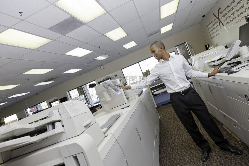 在两台登记机之间印刷机工作的印刷厂工作人员图片