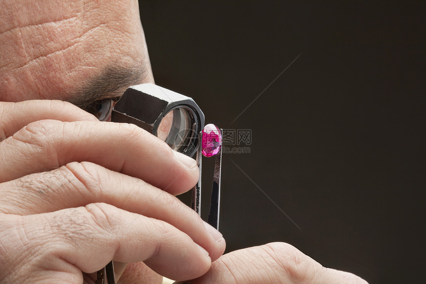 珠宝商在黑色背景上检查珠宝的剪裁图像图片