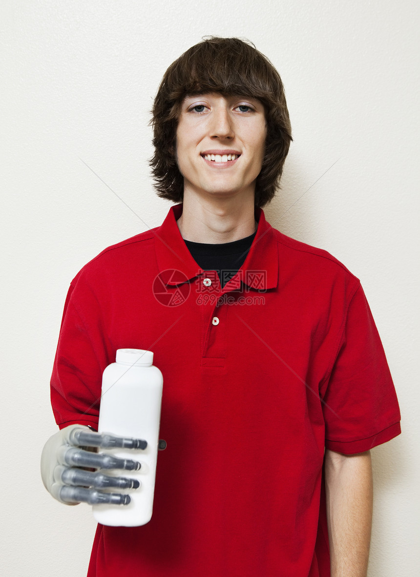 一个快乐的年轻男子拿着瓶装假肢 手放在灰色背景上的肖像图片