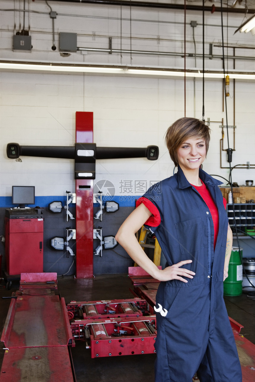 汽车修理店内手摸臀部的年轻快乐女机械工图片