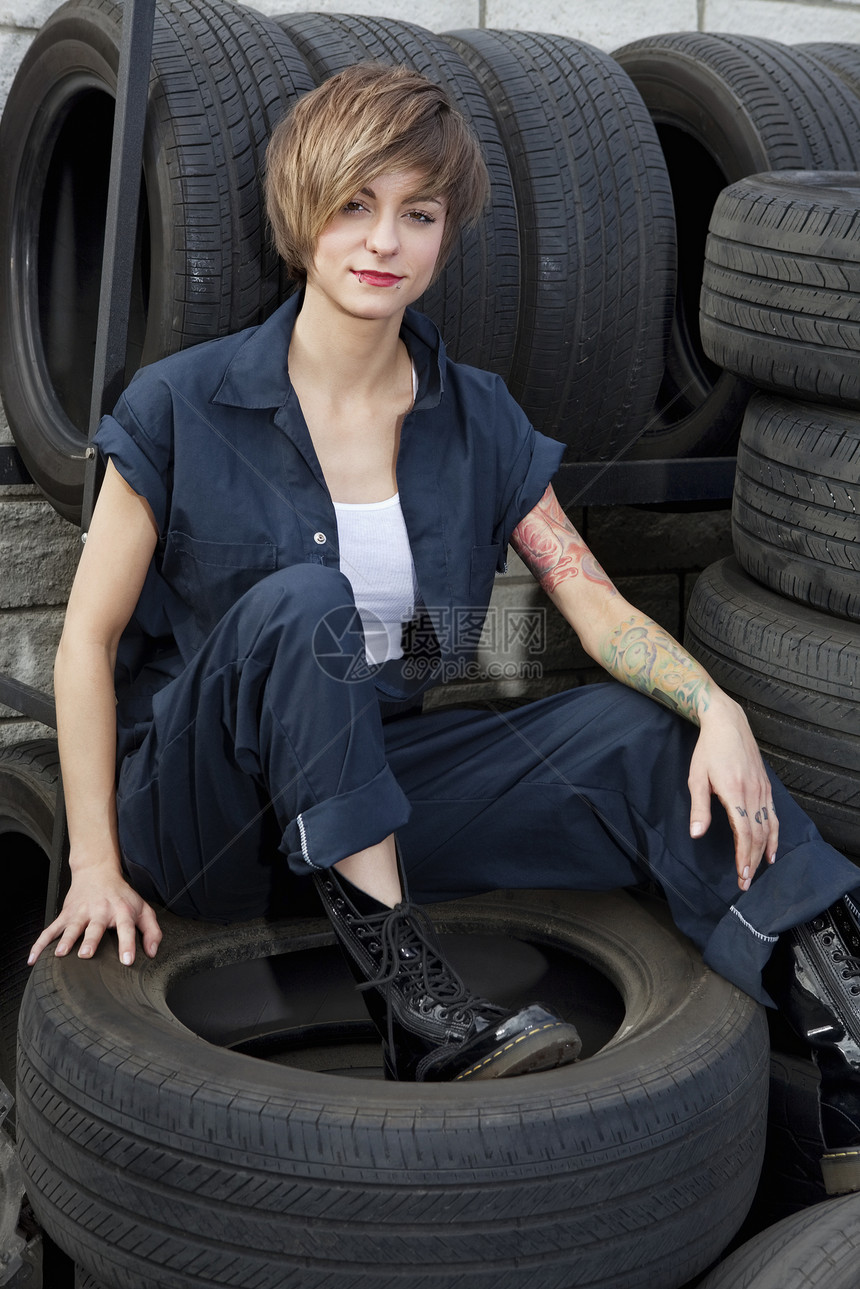 坐在汽车车间轮胎上的一个年轻机械工的肖像图片