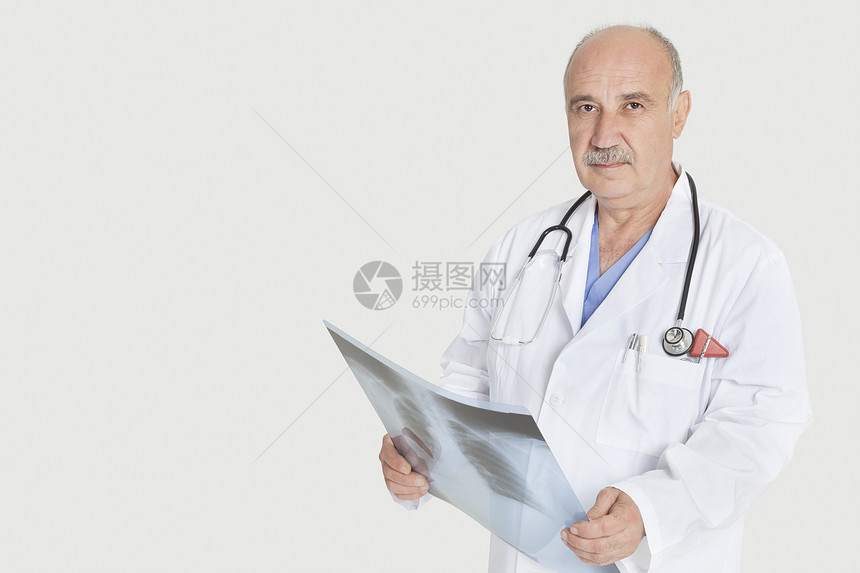 在灰色背景上进行X光检查的高级男性执业医师肖像图片