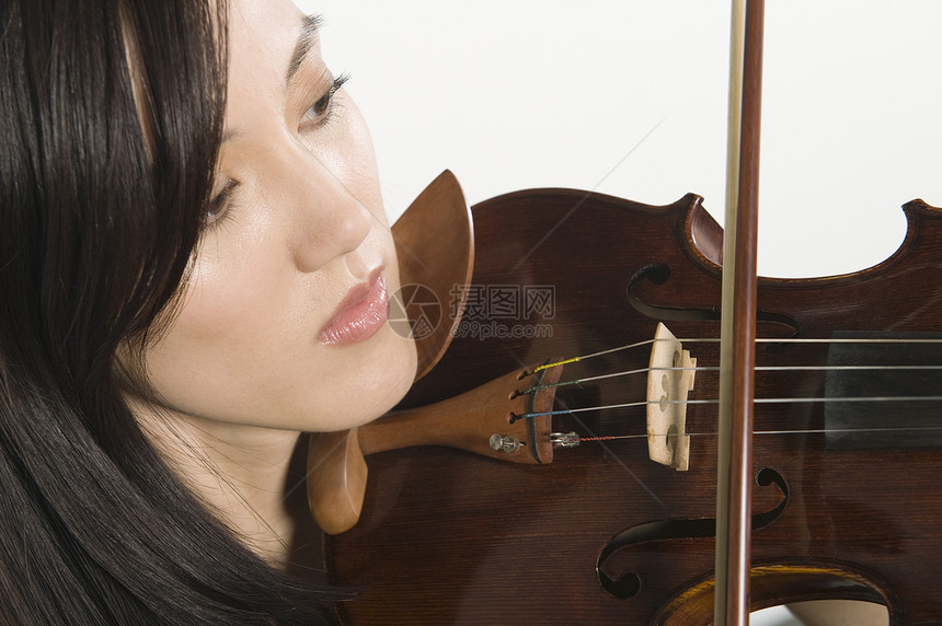 特写在白色背景中孤立的女青年拉小提琴图片