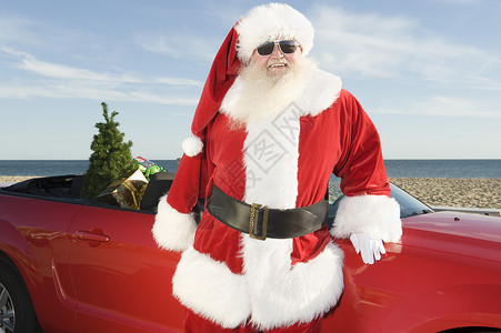 圣诞之父站在红敞篷车和圣诞树旁边舞会位置跑车车辆胡须夹克胡子衣服海滩男人背景图片