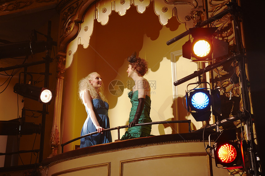两名年轻妇女在戏剧箱中交谈的低角度视角图片
